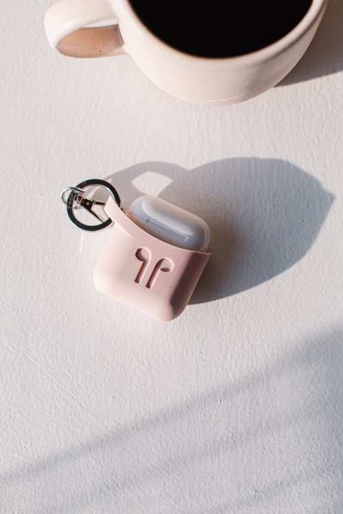 Wireless Earbuds In A Pink Case Lay On A Table Photo