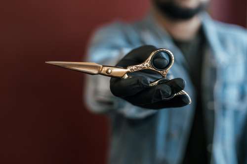 Hand Holds Out Elegant Gold Scissors Photo
