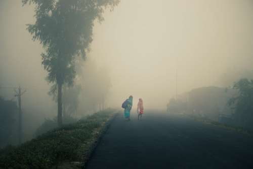 Two People Walk On An Empty Foggy Road Photo