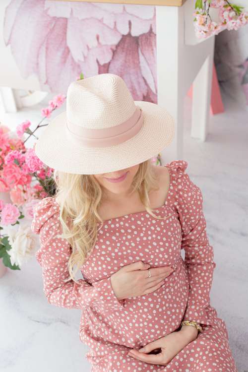 Person In A Pink Polka Dot Dress And White Hat Looks Down Photo