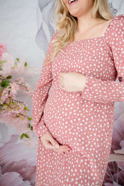 Woman In Pink Dress Stands And Holds Her Belly Photo