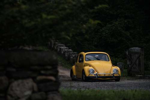 A Yellow Car Parked On A Lush Country Road Photo