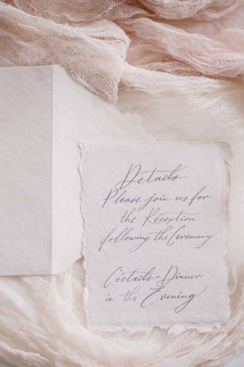 An Invite Lays Surrounded By Soft Pink Fabric Photo