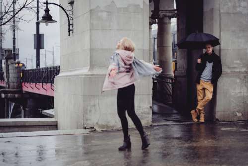 Young man watching his girlfriend dance in the rain