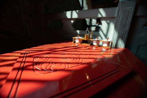 Red Table With Carved Inlay Is Bathed In Sunlight Photo