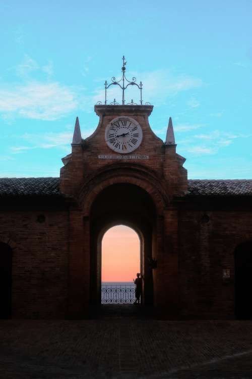 Person Standing In A Courtyard Archway At Sunset Photo