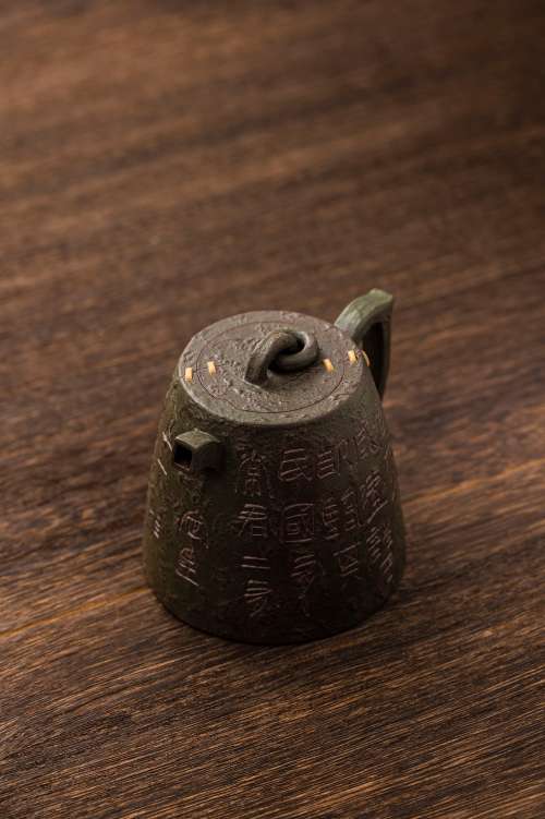 Metal Teapot With Gold Lines And Carved Surface Photo