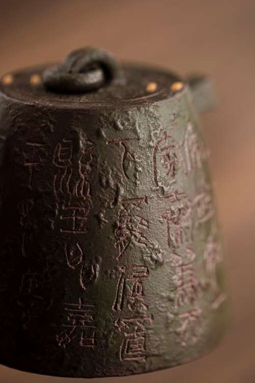 Close Up Of A Metal Teapot With Text Carved Into It Photo