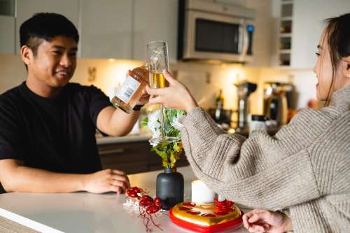 Couple Raises Their Glasses To Cheers In Their Kitchen Photo