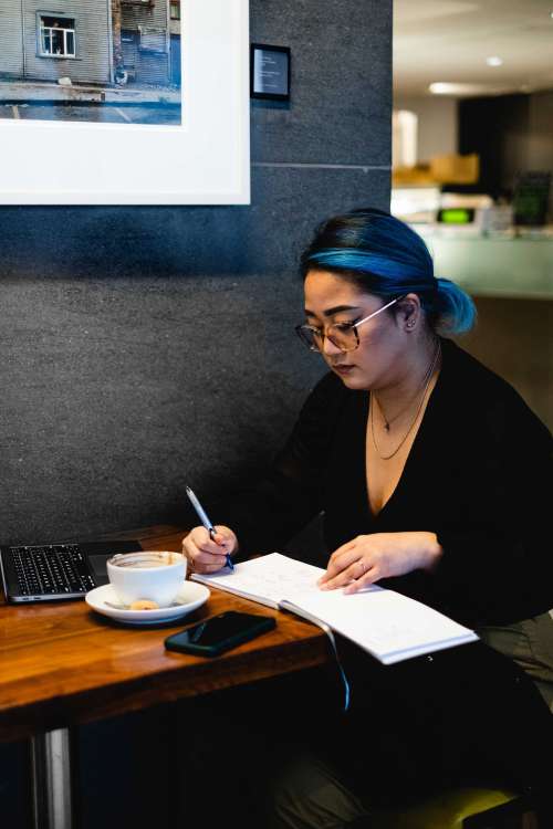 A Woman Sits Alone In A Coffee Shop Writing Photo
