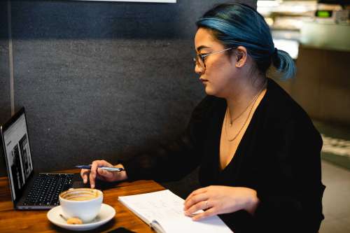 Woman Sits Alone In A Quiet Cafe With A Notebook And Laptop Photo