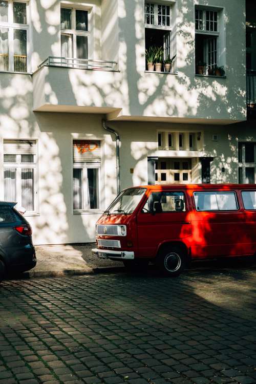 Vintage Red Van Parked Beside A White Building Photo
