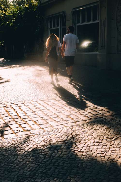 Couple Holds Hands And Walks On Stone Sidewalk Photo