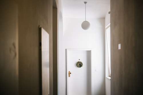 White Hallway With A White Door And Green Wreath Photo