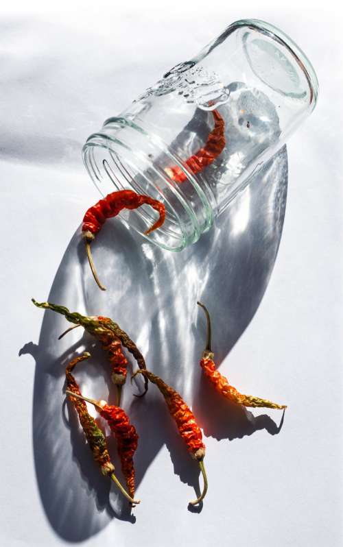 A Glass Jar With Red Chili Peppers Falling Out Of It Photo