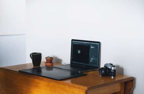Home Office With A Laptop And Film Camera On Wooden Table Photo