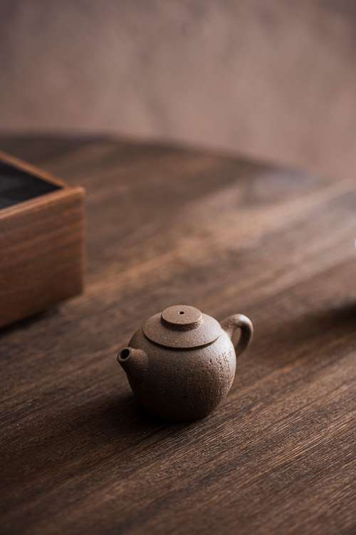 A Tiny Carved Teapot Sits On A Wooden Table Photo