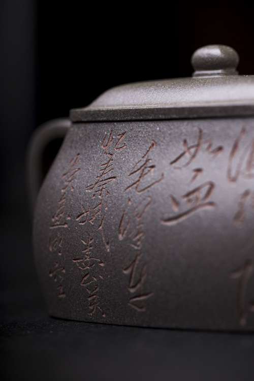 A Close Up View Of Letters Carved On A Grey Teapot Photo