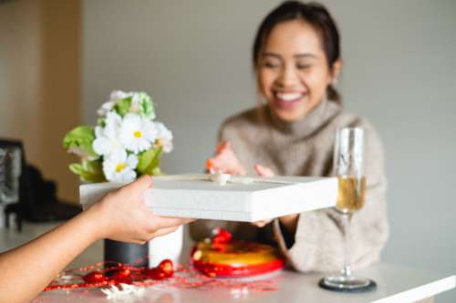 Woman Smiles As An Arm Reaches To Give Her A Wrapped Gift Photo