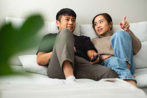 A Couple Sit On A Their Couch In Conversation Photo