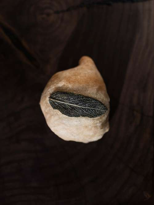 A Bun Topped With A Sage Leaf On A Cutting Board Photo