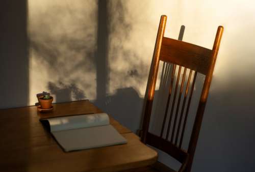 Wooden Table And Chair With A Notebook And Small Plant Photo