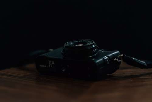 Black Camera Lays On Wooden Table Photo