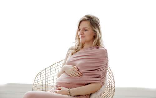 Person Wearing Pink Sits While Holding Their Belly Photo