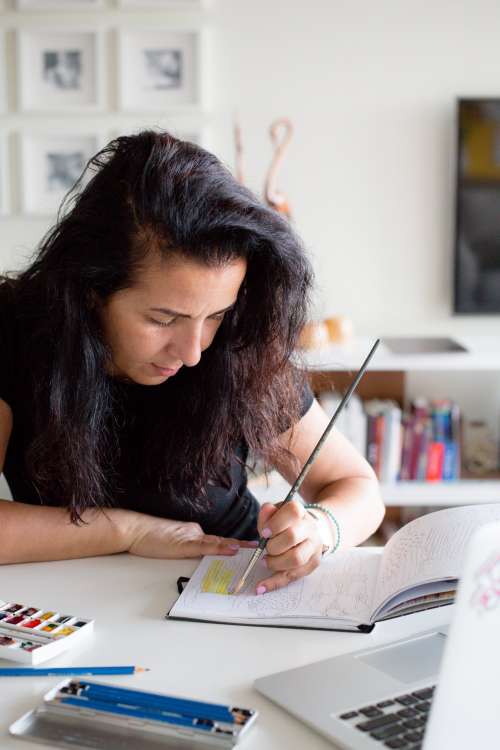 Person Carefully Paints In A Sketchbook Photo