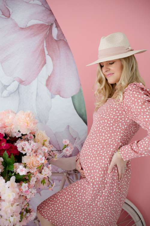 Person In A Pink Dress And A Hat Holds There Belly Photo