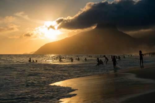Sunsets On A Beach With People Swimming Photo