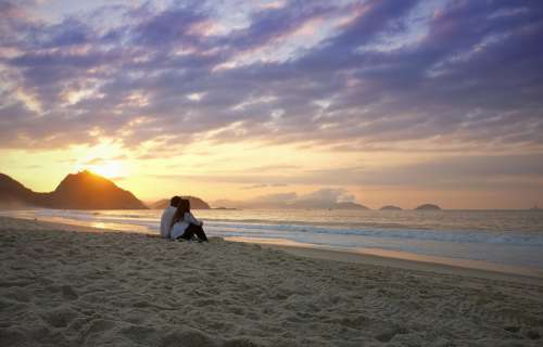 Two People Sit On The Beach And Watch The Sunset Photo