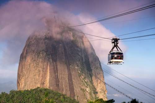 A Square Gondola And Black Cables Reach Up To A Mountain Photo