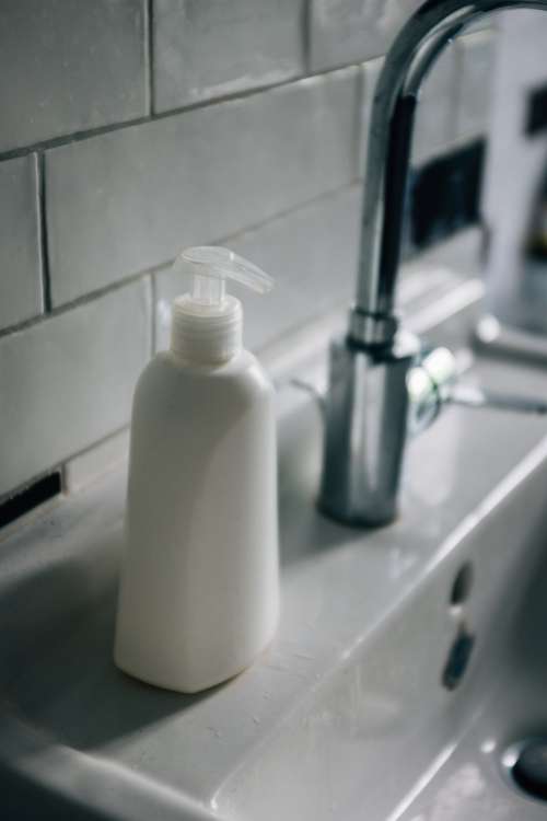 White Pump Bottle Sits On A White Porcelain Sink Photo