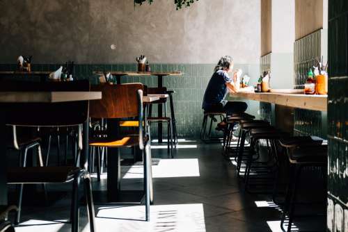 Person Sits Alone By The Window Of A Quiet Restaurant Photo