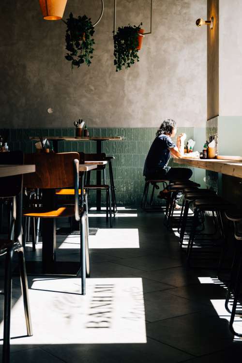 Person Enjoys Lunch Alone In A Sunlit Restaurant Photo