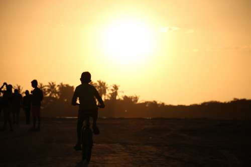 A Silhouette Of A Person Riding A Bike At Sunset Photo