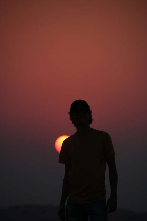Silhouette Of A Person With A Baseball Cap Against A Setting Sun Photo