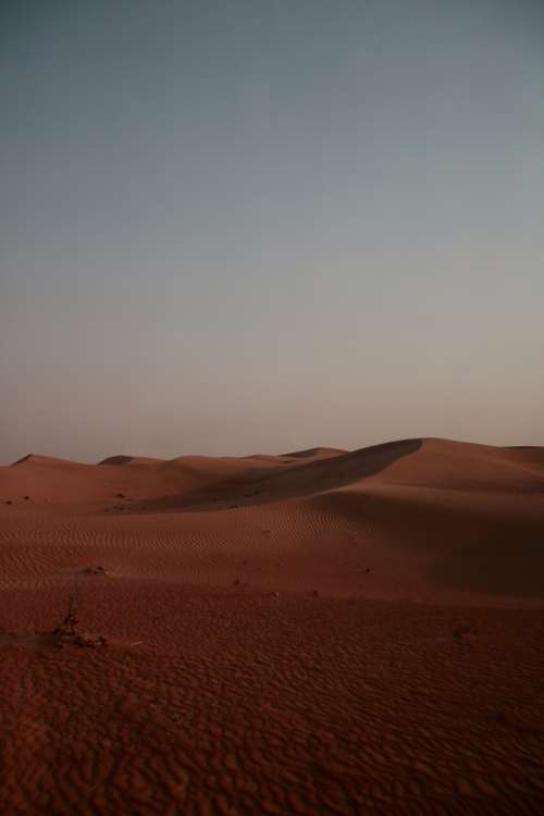 A Landscape Of Rust Colored Sand Dunes Photo