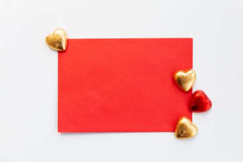 Flatlay Of A Red Envelope With Gold And Red Chocolates Photo