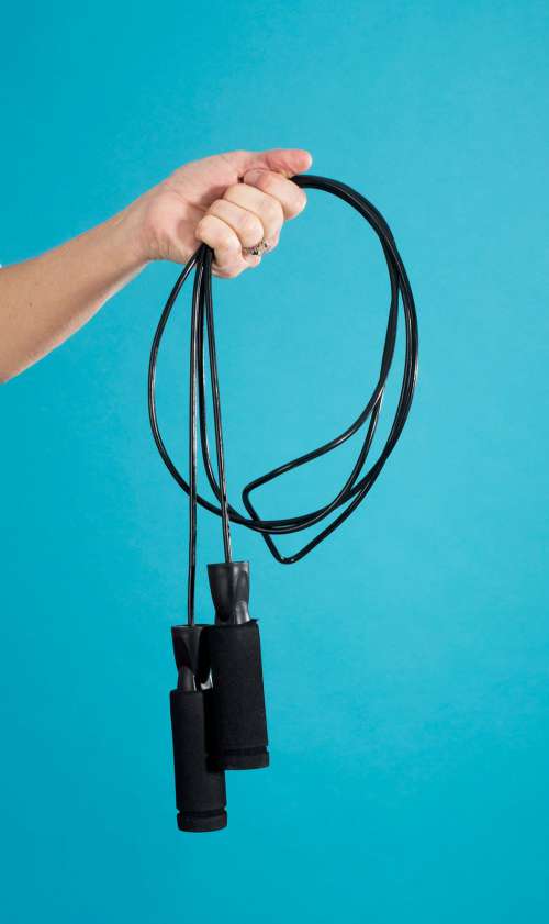 A Hand Grips A Black Gathered Jump Rope Photo
