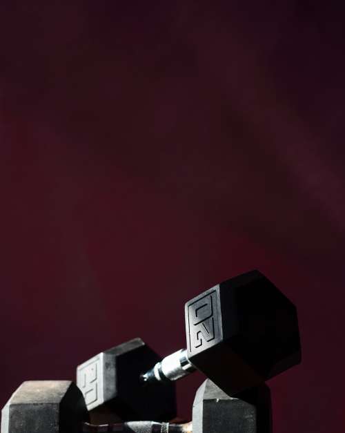 Two Dumbells Against A Dark Red Background Photo