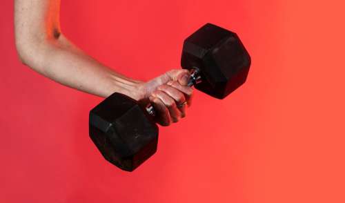 Hand Grips A Dumbbell Against A Vibrant Red Background Photo