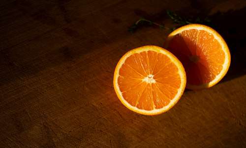 Two Slices Of Orange Lay On A Sunlit Cutting Board Photo