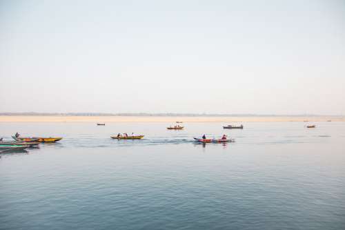 Calm Water With People Rowing Multiple Thin Boats Photo