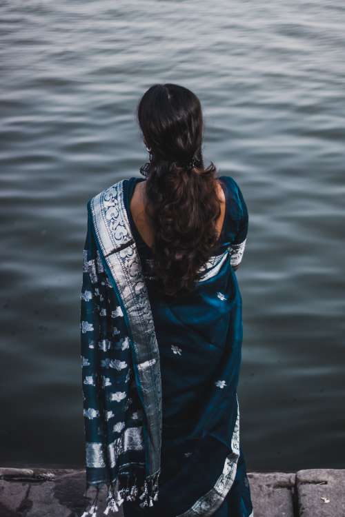 Person Wrapped In Blue And Silver Looks Out To Water Photo