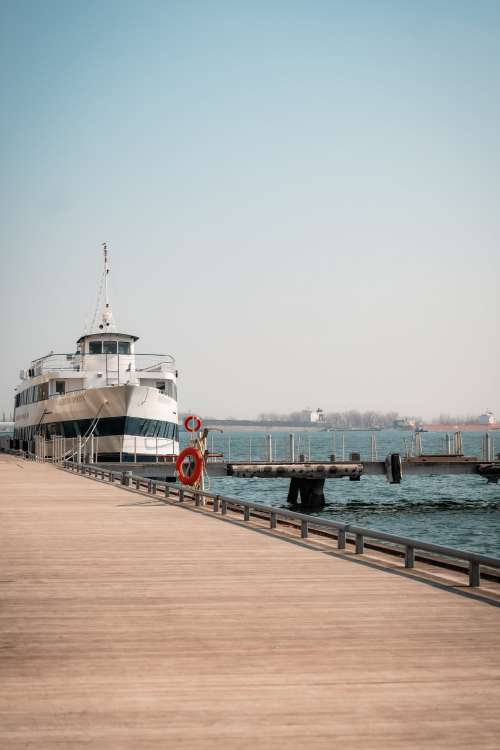 Large White Boat Docked By A Wooden Boardwalk Photo