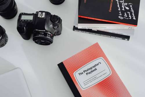 Photographer's desk - books, DSLR camera and lenses