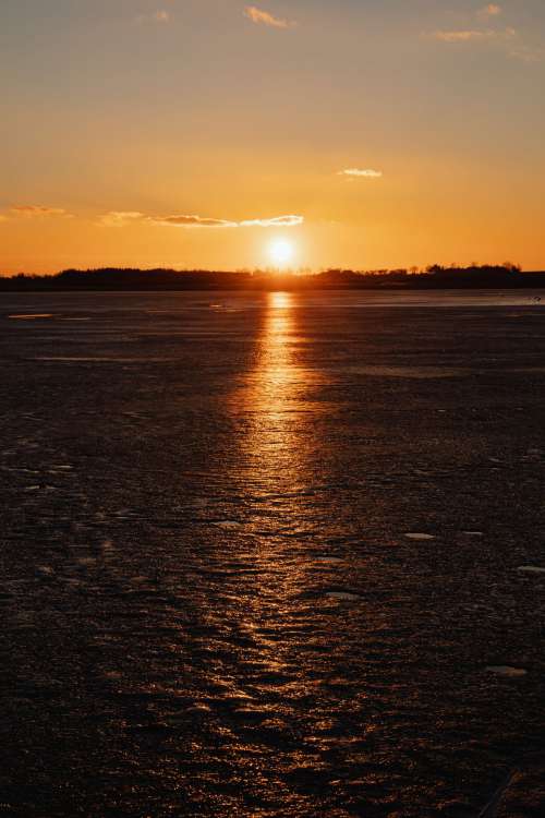 Melting ice on the lake in winter at sunset