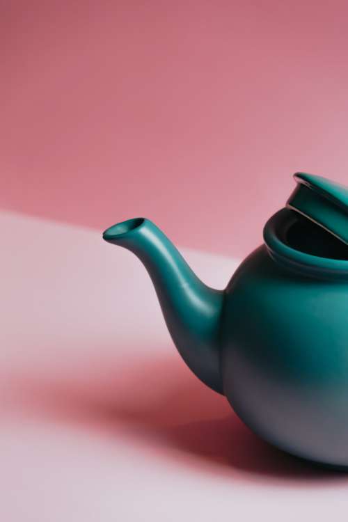 Green Teapot Against A Light Pink Backdrop Photo